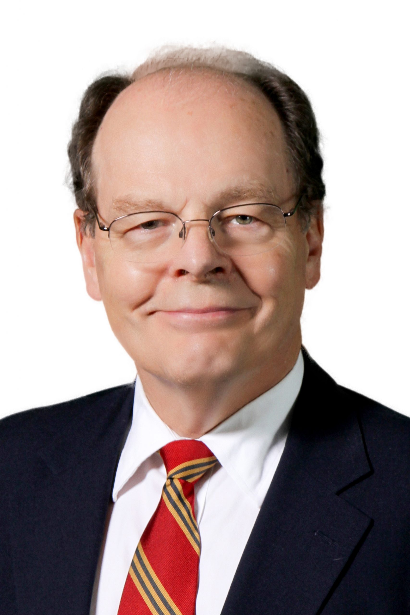 Man in dark suit, white shirt, and red tie wearing glasses and smiling for portrait photo